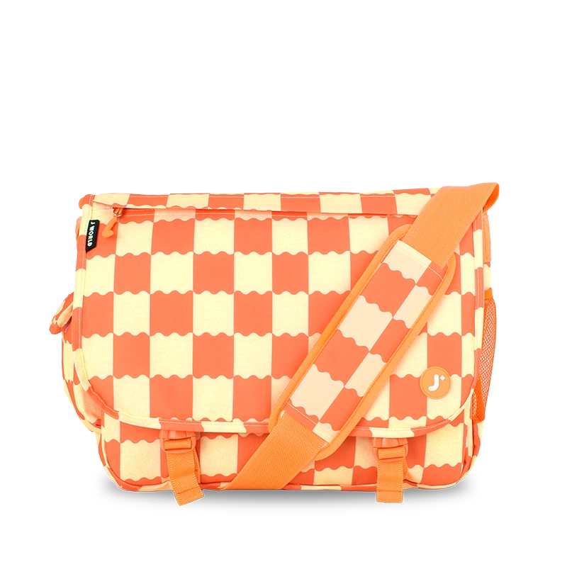 A rectangular messenger bag with a bold orange and cream checkerboard pattern, featuring an orange adjustable shoulder strap and a small circular orange logo on the front pocket.